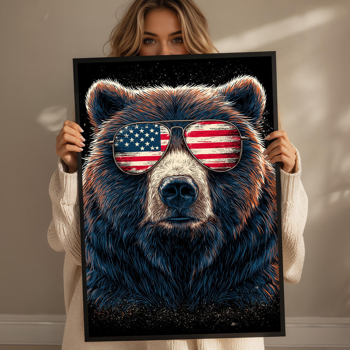 A woman is holding up a framed poster of a bear wearing sunglasses with an American flag design.