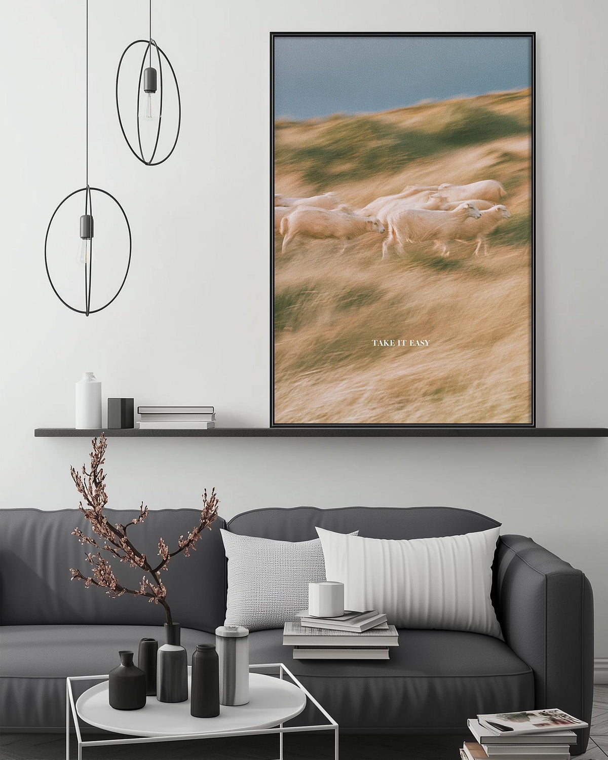 a modern living room with a gray sofa, a coffee table, and a large framed picture of a flock of sheep on the wall.
