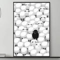a black and white living room with a gray couch, a coffee table, and a large framed artwork depicting a group of sheep with a single black sheep standing out.