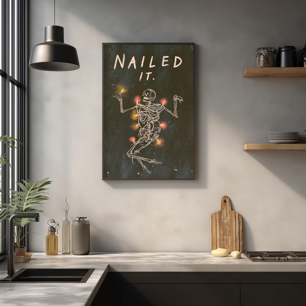 a kitchen counter with various items such as a cutting board, a bottle, and a plant. Above the counter, there is a framed poster or artwork depicting a skeleton with the text "Nailed it" written on it.