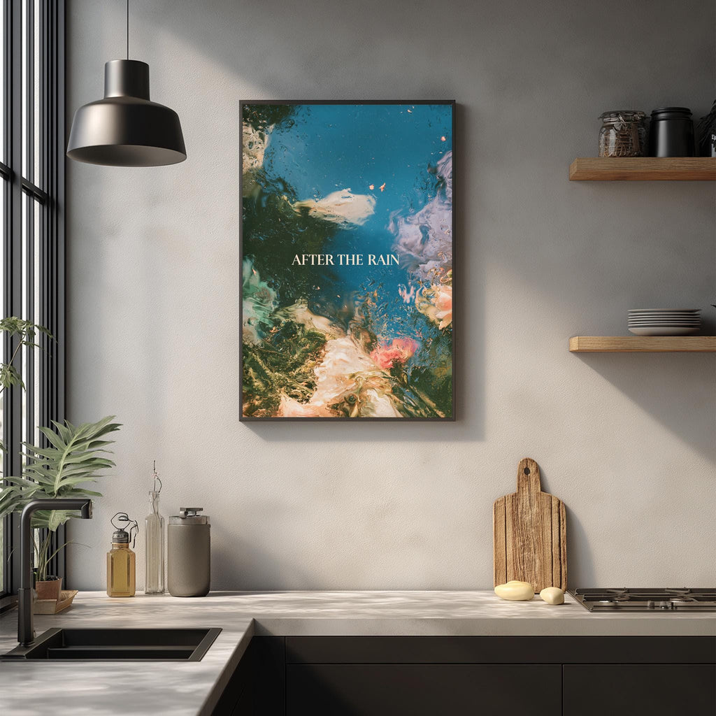 a kitchen counter with various items, including a cutting board, a sink, and a potted plant. Above the counter, there is a framed artwork depicting a colorful underwater scene with the text "AFTER THE RAIN" written on it.