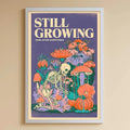 A child's bedroom with a white bookshelf, a stuffed rabbit, and a colorful poster on the wall. The poster features a skeleton surrounded by flowers and mushrooms, with the text "STILL GROWING" written above it.
