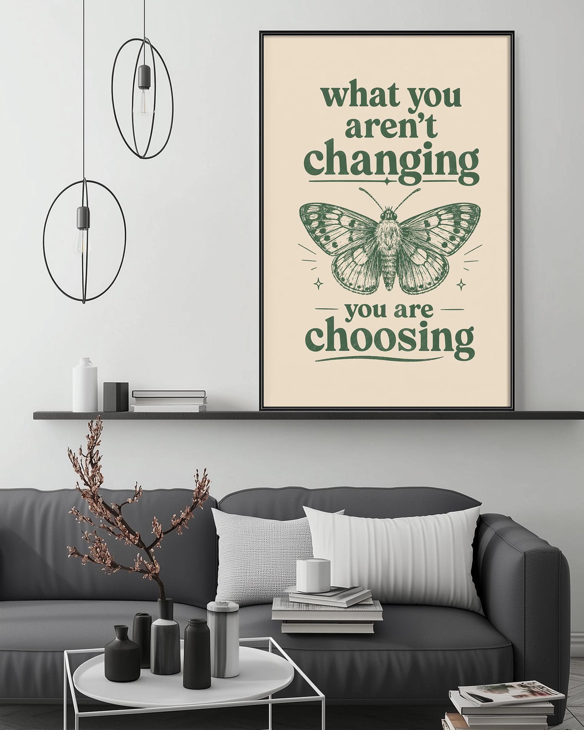a living room with a gray couch, a coffee table, and a framed poster with a butterfly design and the text "what you aren't changing, you are choosing".