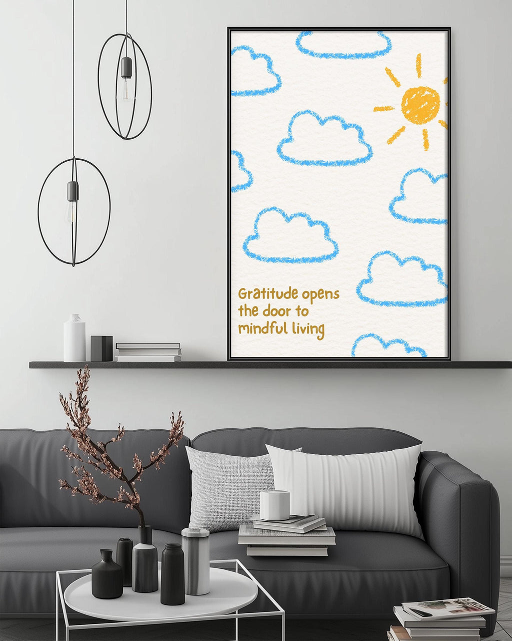 a living room with a gray couch, a coffee table, and a framed poster on the wall. The poster has a drawing of clouds and a sun, along with the text "Gratitude opens the door to mindful living".