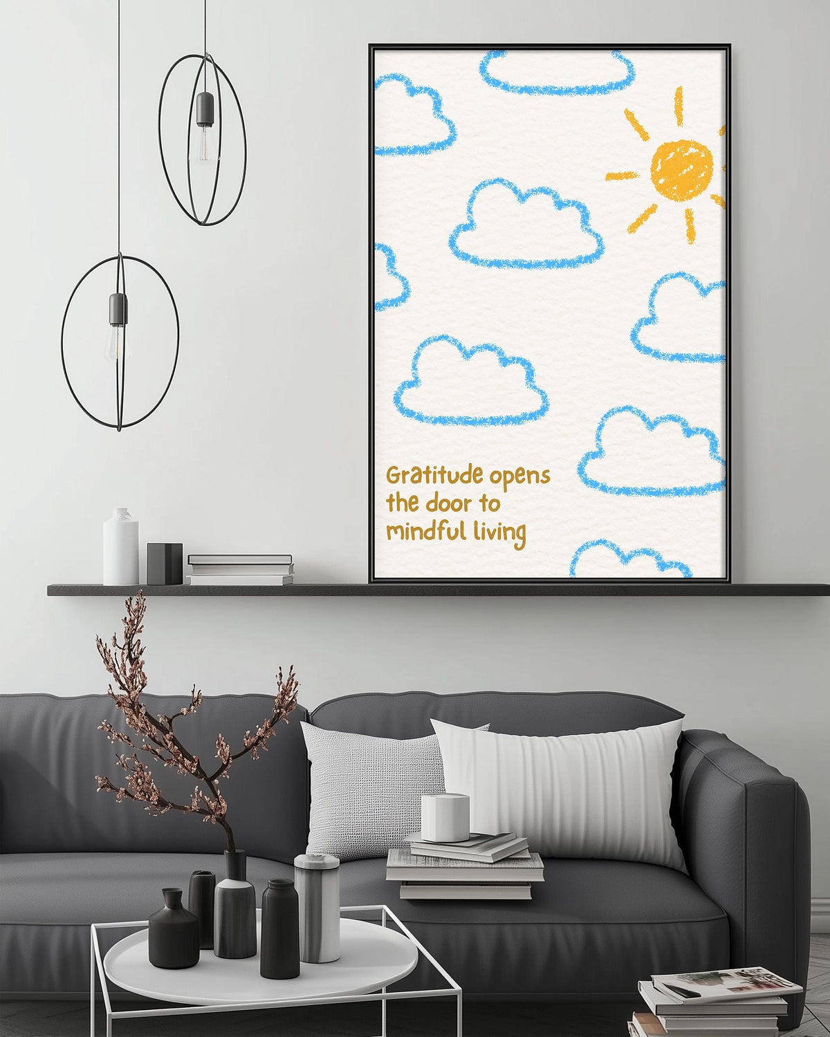 a living room with a gray couch, a coffee table, and a framed poster on the wall. The poster has a drawing of clouds and a sun, along with the text "Gratitude opens the door to mindful living".