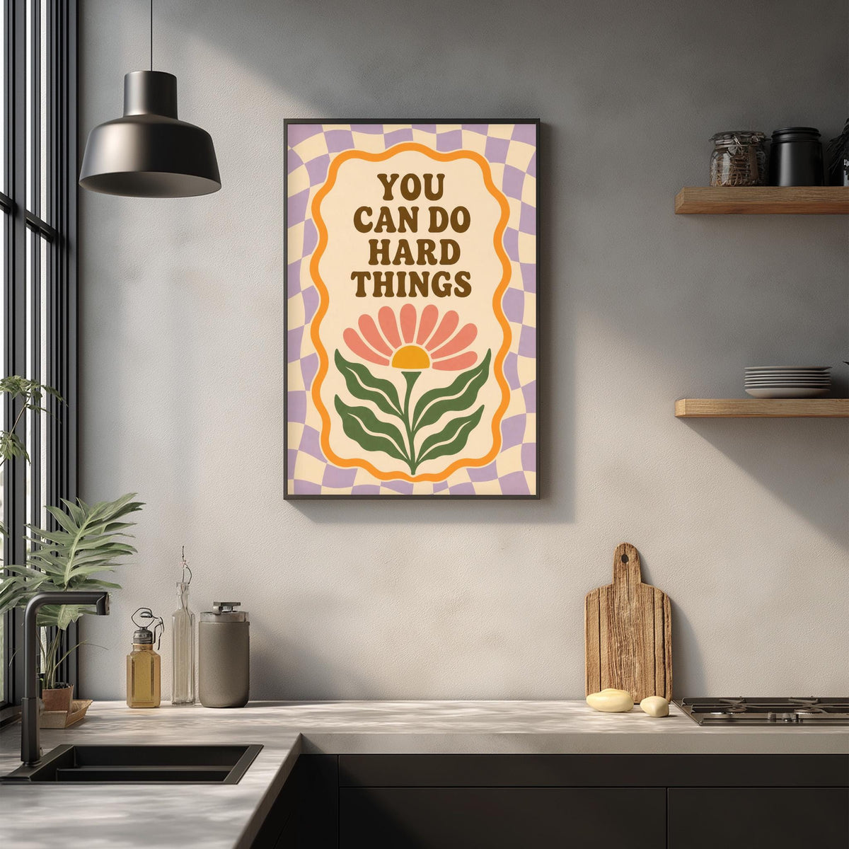 a framed poster with the text "YOU CAN DO HARD THINGS" hanging on a wall above a kitchen counter.