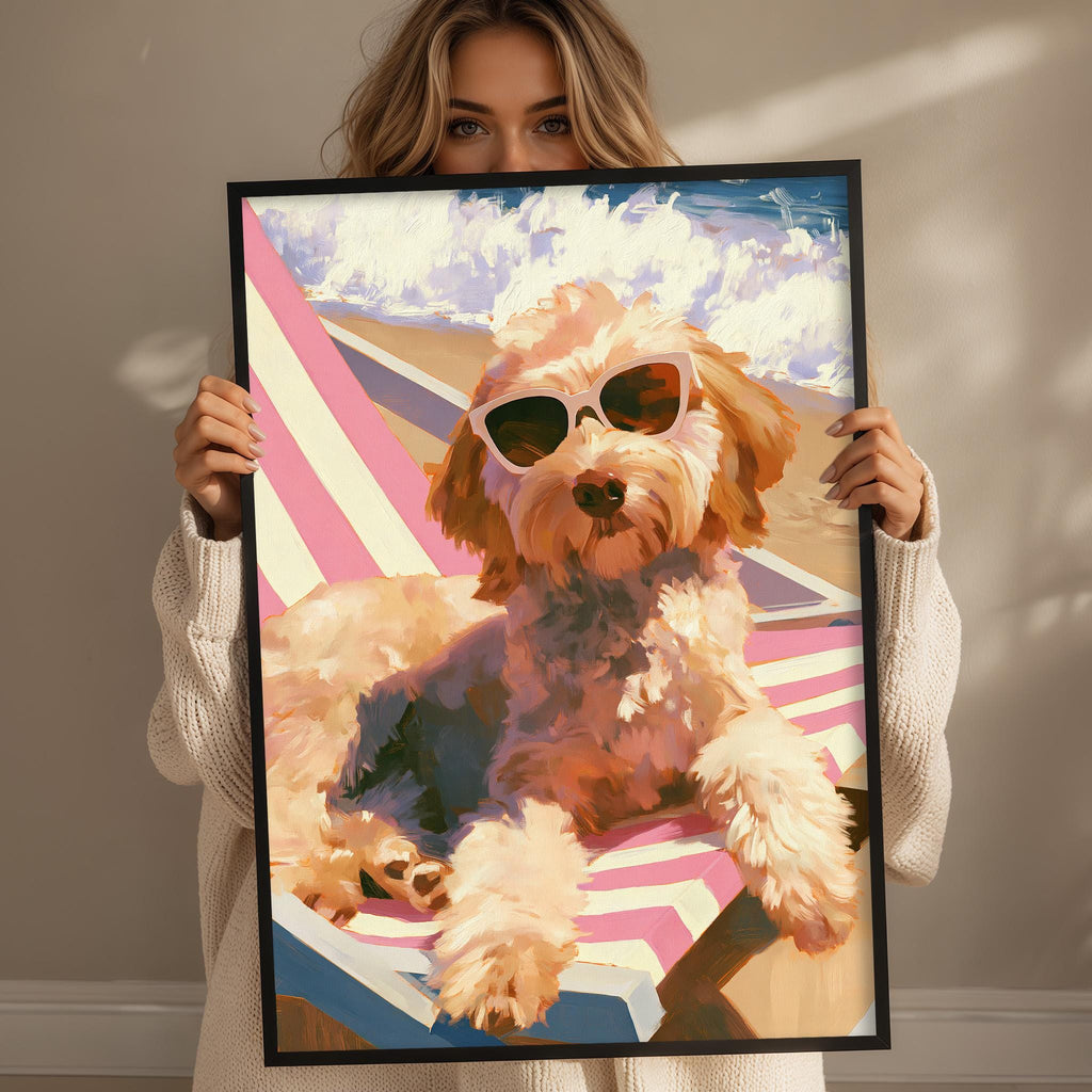 A woman holds up a framed painting of a dog wearing sunglasses, sitting on a beach chair.