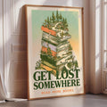 A framed poster with a stack of books on top, surrounded by a forest scene, and the text "GET LOST SOMEWHERE READ MORE BOOKS" is displayed on a wall.