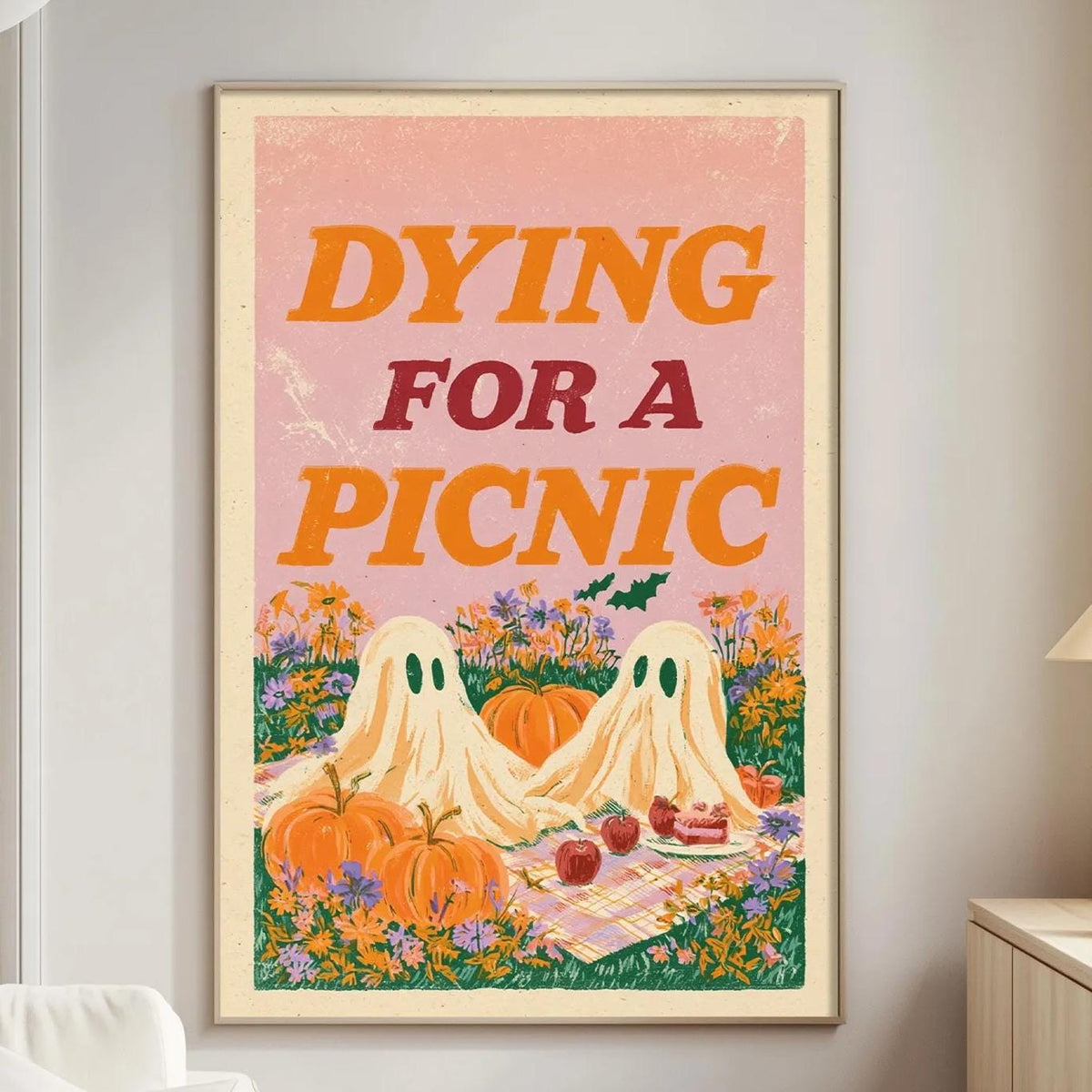 a poster with a Halloween theme, depicting two ghostly figures and a picnic scene, hanging on a wall in a living room.