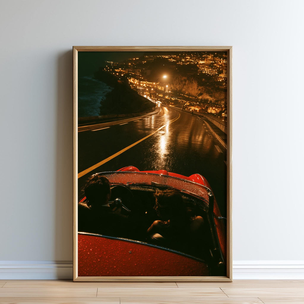 A framed photograph of a red convertible car driving on a wet road at night, with a cityscape visible in the background.