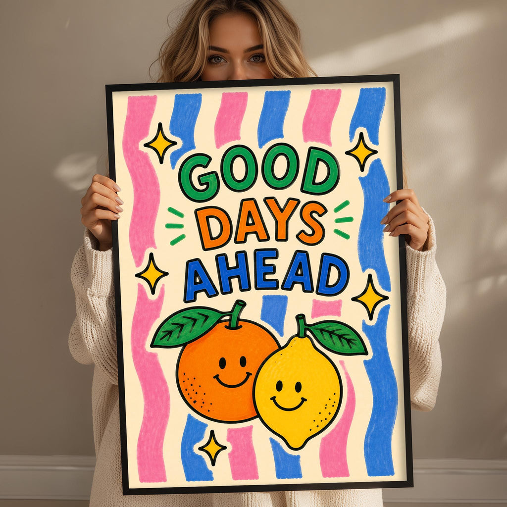 A woman holding a framed poster with a colorful design featuring two smiling fruits, an orange and a lemon, along with the text "GOOD DAYS AHEAD".