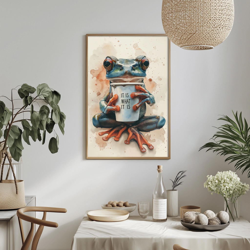 a framed painting of a frog holding a coffee cup, with the text "IT IS LIKE A DRINK AT ITSELF" written on the cup. The painting is displayed on a wall above a dining table with various decorative items, such as potted plants, vases, and bowls.