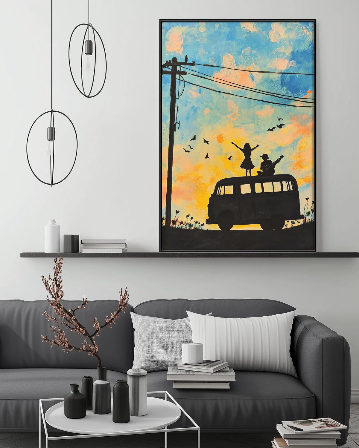 a living room with a gray sofa, a coffee table, and a large framed painting depicting a van with two people on top. The painting is hanging on the wall above the sofa.