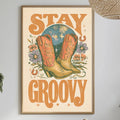 a framed poster with the text "STAY GROOVY" hanging on a wall above a dining table with various items on it, including a bottle, a bowl, and a vase.
