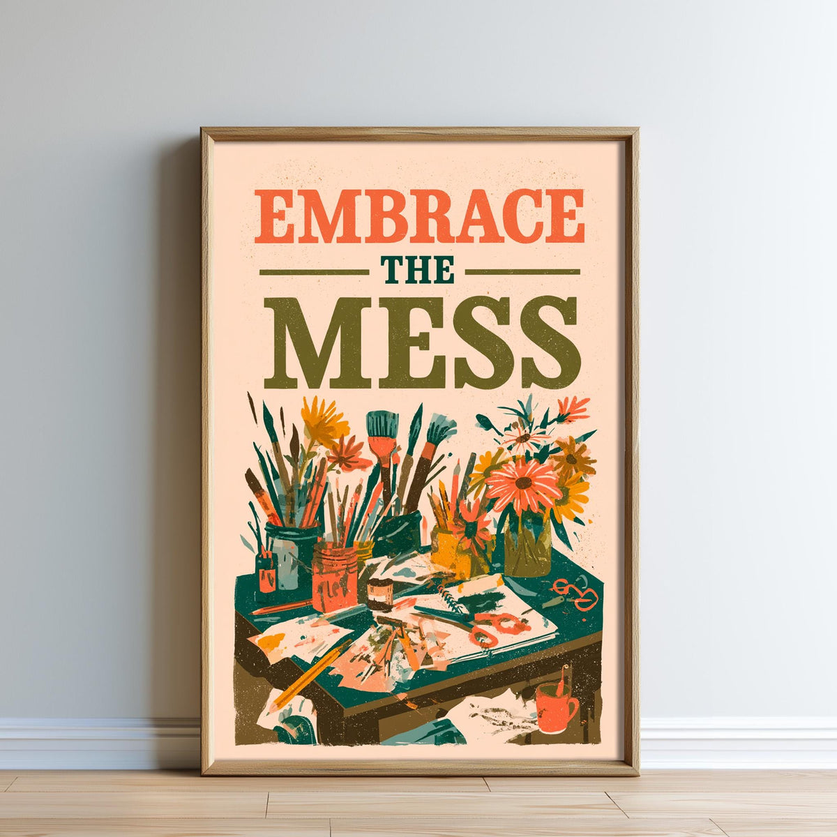 The image is a framed poster with a colorful illustration of various art supplies, including paintbrushes, paint tubes, and flowers. The text on the poster reads "Embrace the mess" and is displayed prominently in the center of the poster.