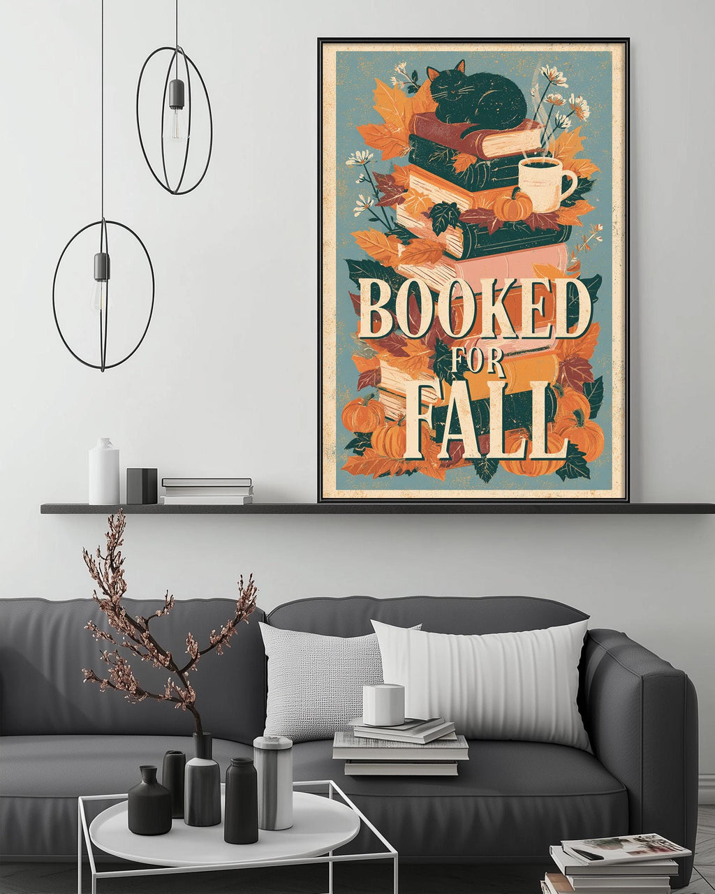 a cozy living room with a gray couch, a coffee table, and a bookshelf. Above the couch, there is a framed poster with the text "BOOKED FOR FALL" and an illustration of books, pumpkins, and a cat.
