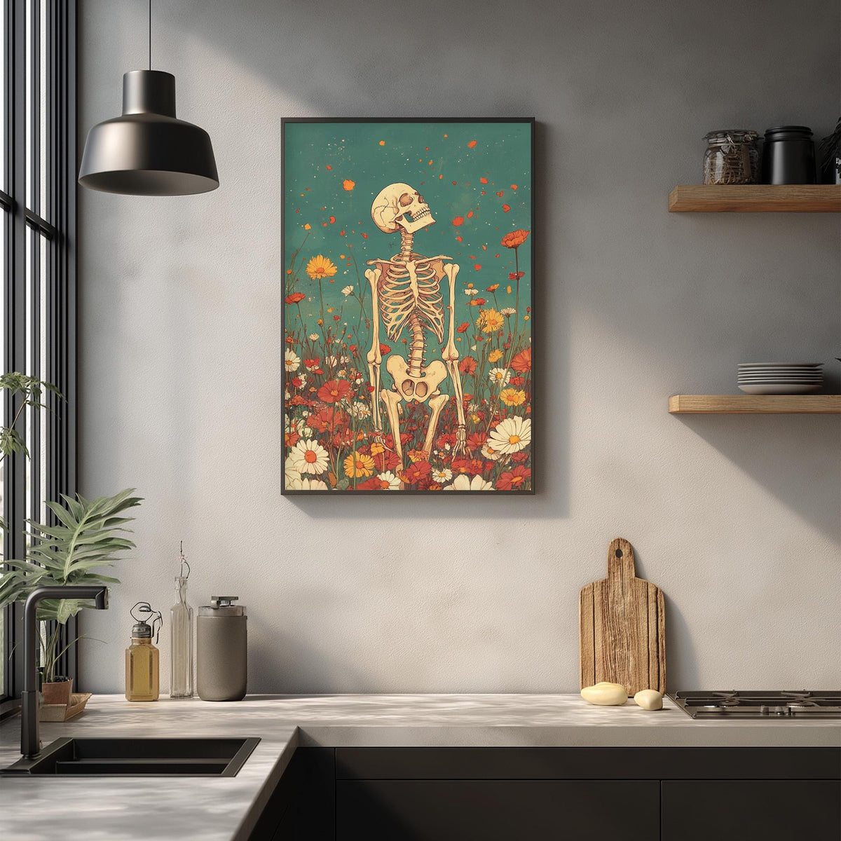 a kitchen counter with various items, including a potted plant, a cutting board, and a sink. Above the counter, there is a framed artwork depicting a skeleton standing in a field of flowers.