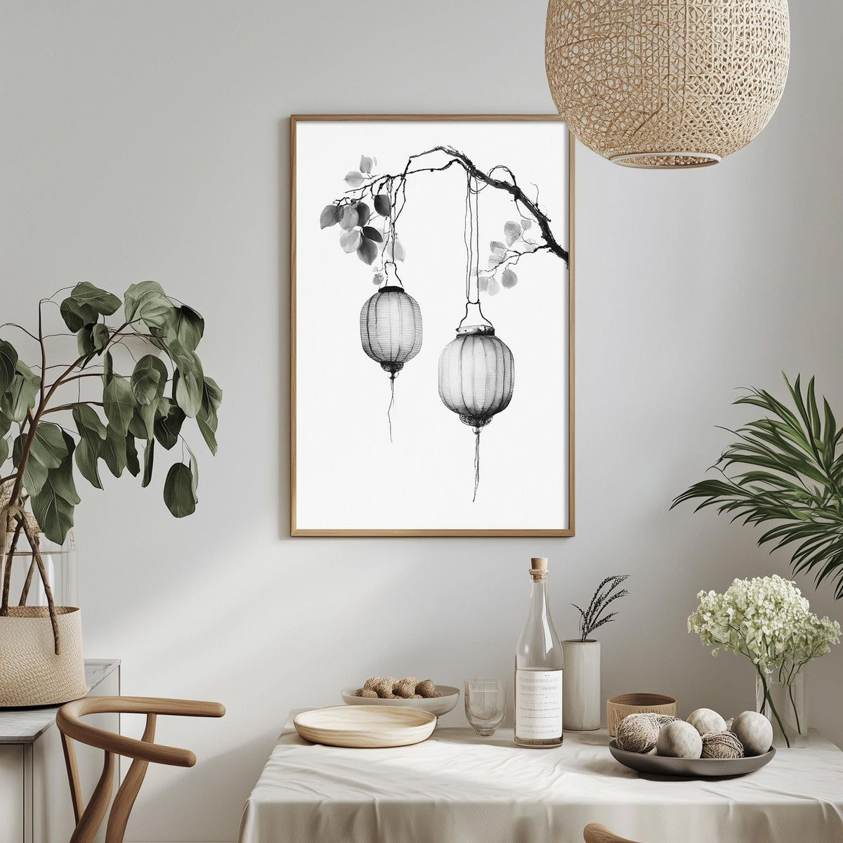 a minimalist dining room with a white tablecloth, a framed picture of two hanging lanterns, and various decorative elements such as potted plants and vases.