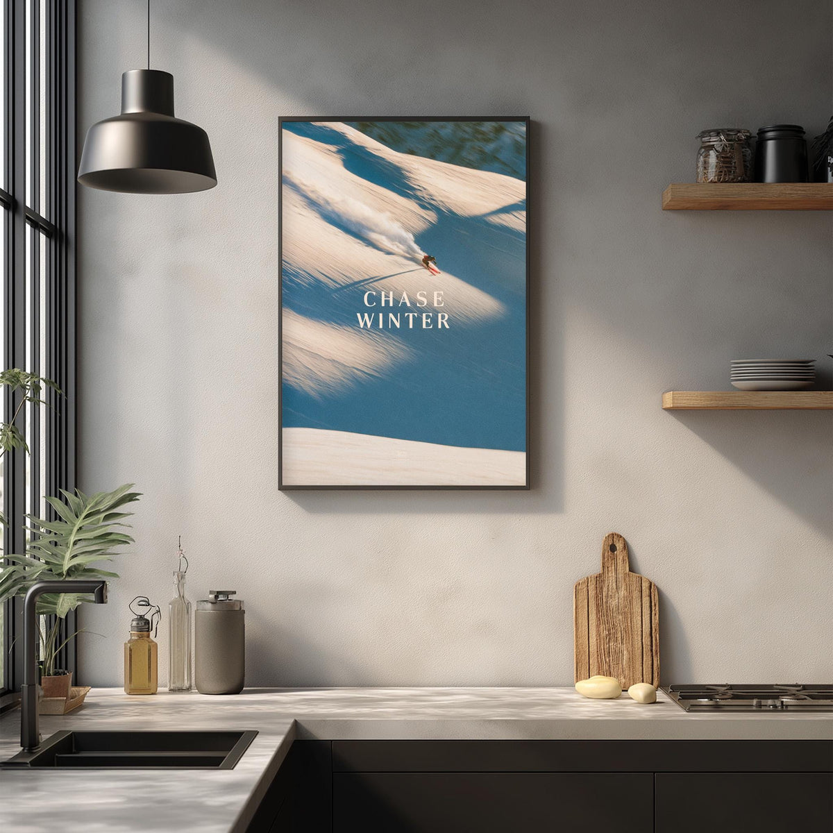 a kitchen counter with various kitchen items, such as a cutting board, a bottle, and a bowl, as well as a framed poster of a person skiing on a snowy mountain.