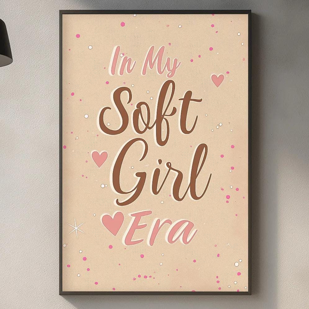 a kitchen counter with various kitchen items, such as a cutting board, a soap dispenser, and a potted plant. Above the counter, there is a framed poster with the text "In My Soft Girl Era" written on it.