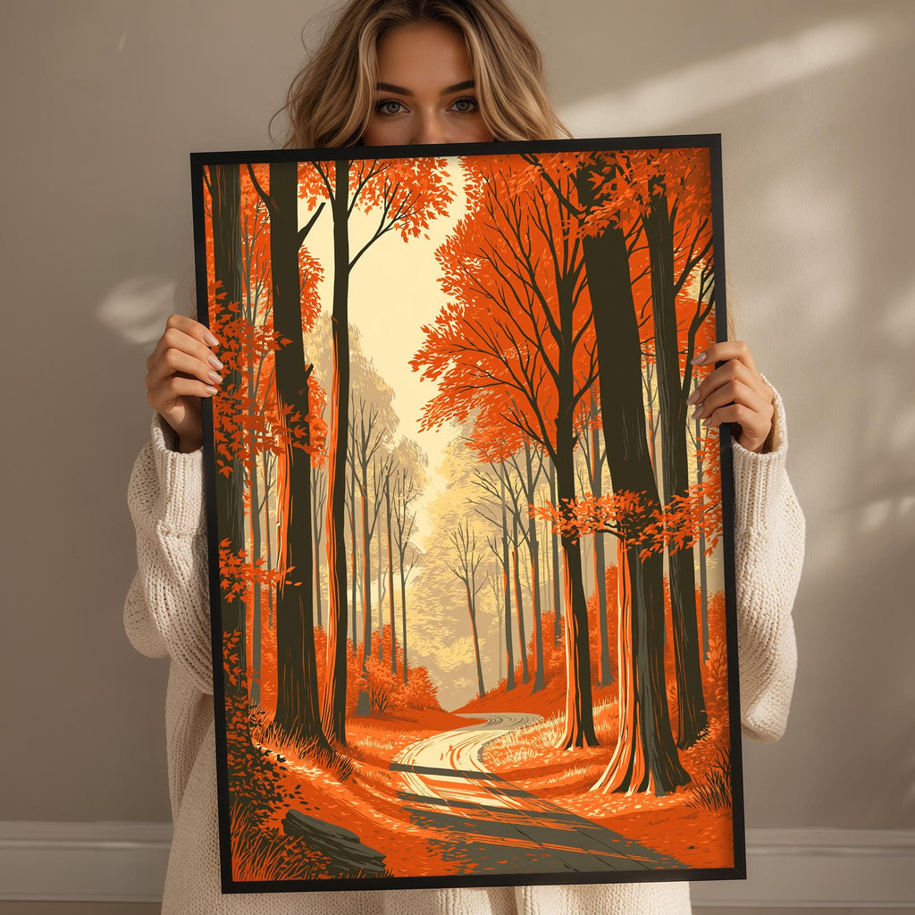 A woman holds up a framed painting depicting a forest scene with a winding path and trees displaying vibrant orange leaves.
