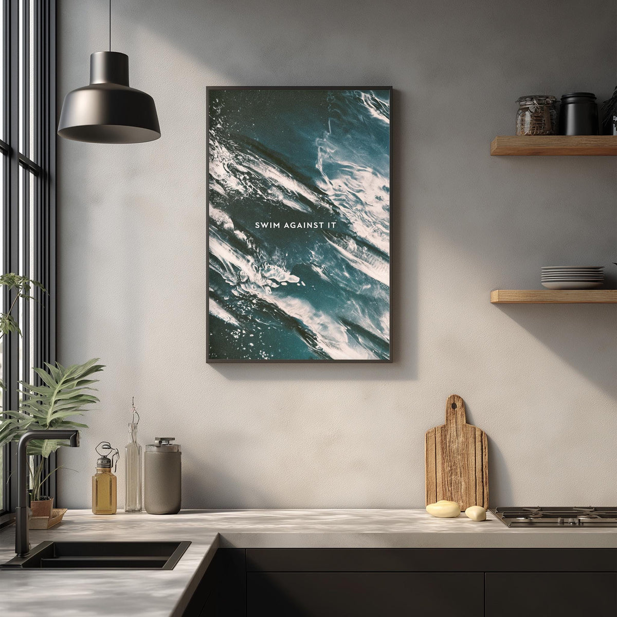 a kitchen counter with a framed poster of ocean waves above it, a wooden cutting board, and various kitchen items such as a bottle, a cup, and a bowl.
