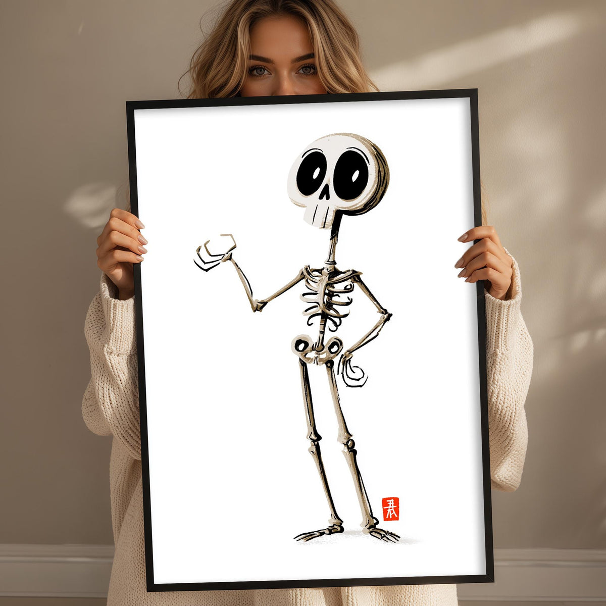 A woman is holding up a framed illustration of a skeleton with a cartoon-like style.