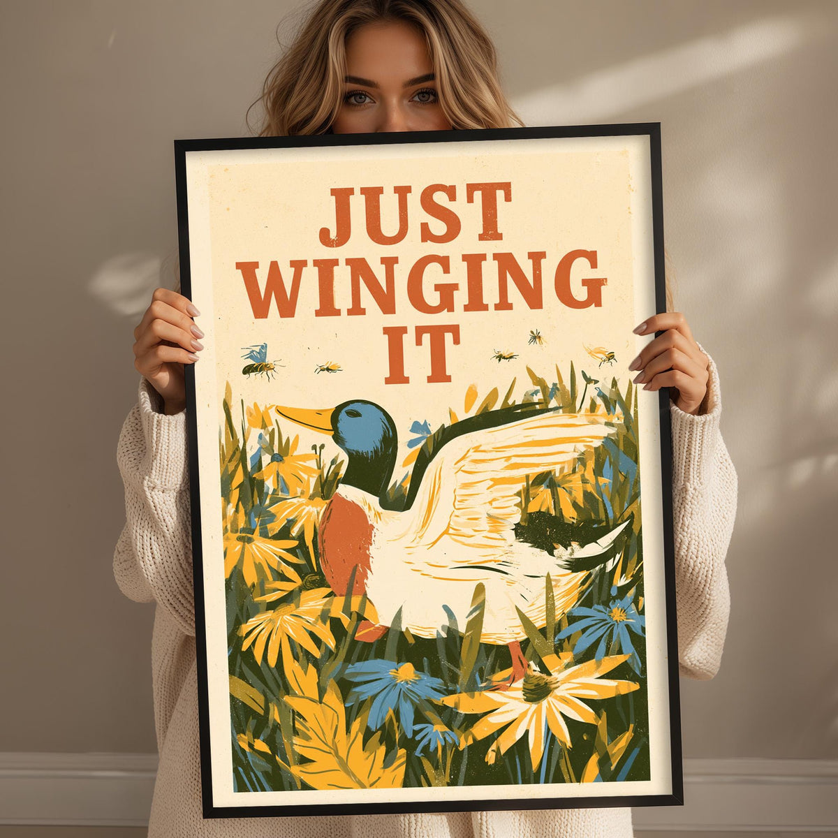 A woman is holding up a framed poster with a colorful illustration of a duck surrounded by flowers and plants.