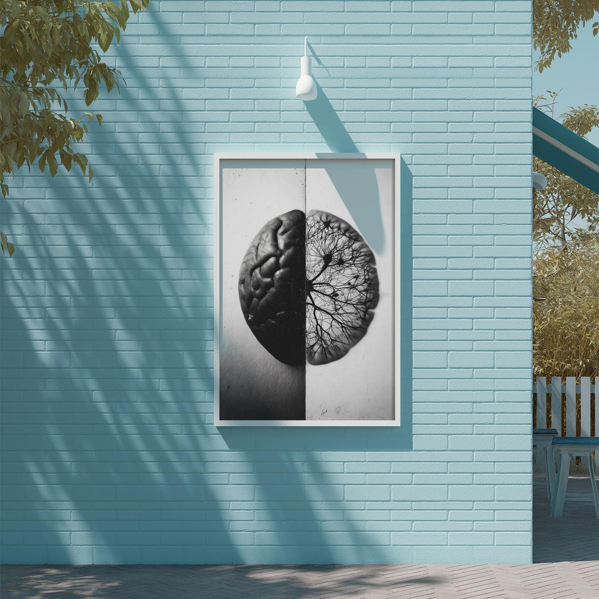 a framed black and white photograph of a brain, with one half appearing to be a brain and the other half being a tree. The photograph is mounted on a blue brick wall, and there is a white light fixture above it.