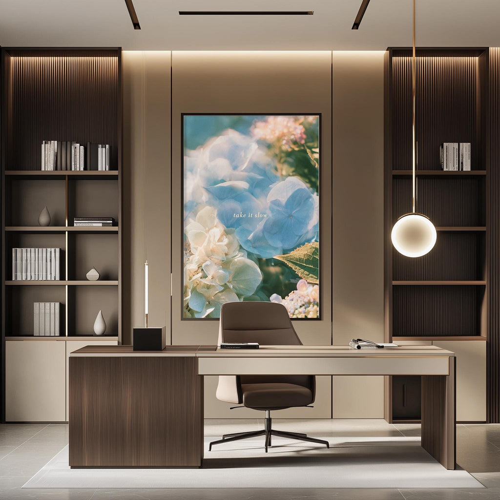 a modern and well-designed office space with a large framed floral artwork on the wall, a wooden desk with a chair, and built-in bookshelves.