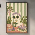 a kitchen scene with a framed illustration of a cat wearing sunglasses, surrounded by various kitchen items such as a potted plant, a cup, and a book.