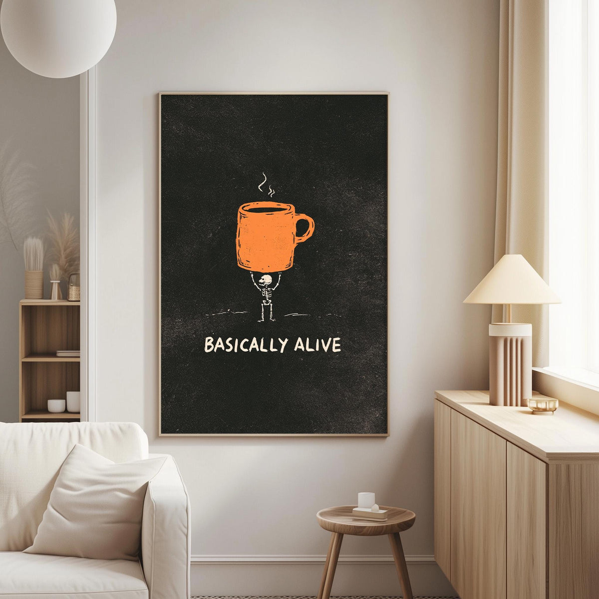 a living room with a white couch, a wooden side table, and a lamp. Above the couch, there is a framed poster with an illustration of a person holding a coffee mug and the text "BASICALLY ALIVE".