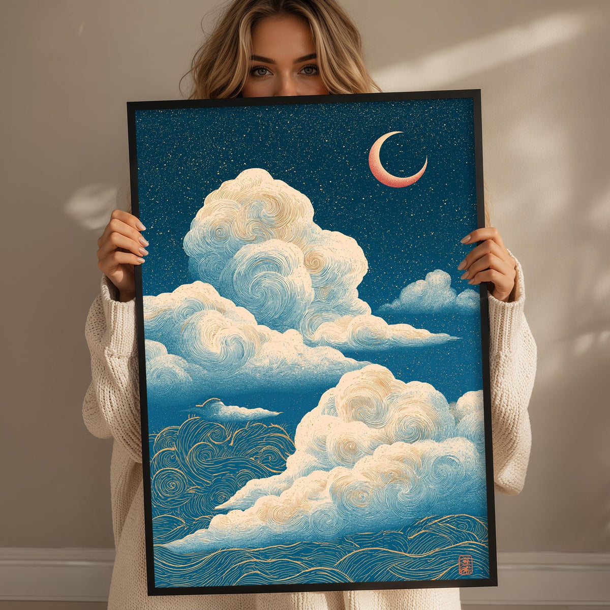 A woman holds up a framed artwork depicting a night sky with a crescent moon and swirling clouds.
