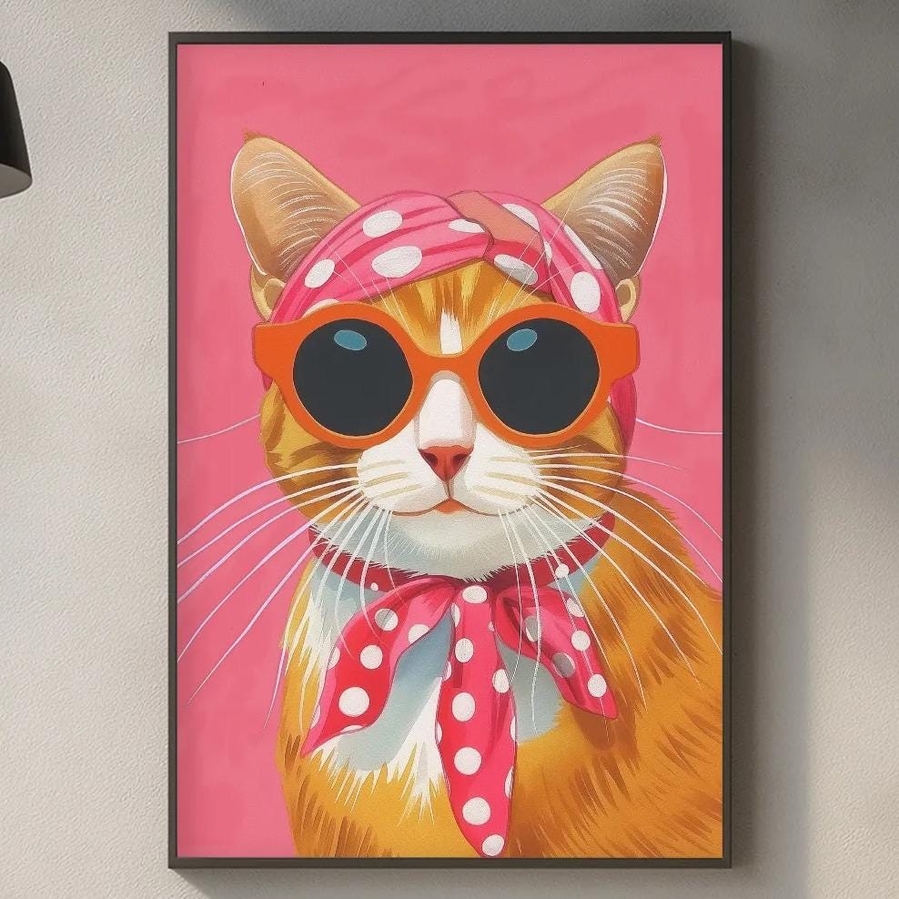 a kitchen counter with a framed picture of a cat wearing sunglasses and a pink scarf hanging on the wall above it.