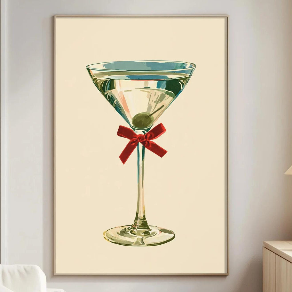 a framed illustration of a martini glass with a red ribbon, hanging on a wall in a living room setting.