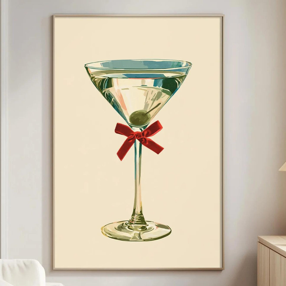a framed illustration of a martini glass with a red ribbon, hanging on a wall in a living room setting.