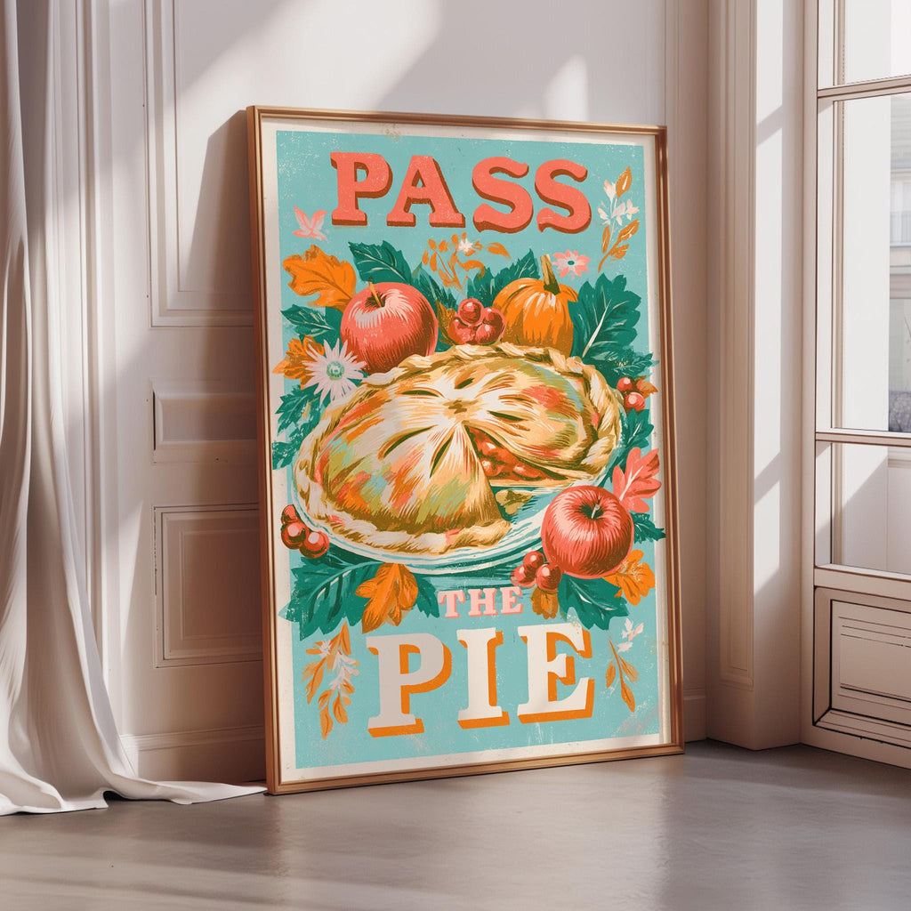 A framed poster with a colorful illustration of a pie surrounded by autumn leaves and fruits, along with the text "PASS THE PIE".