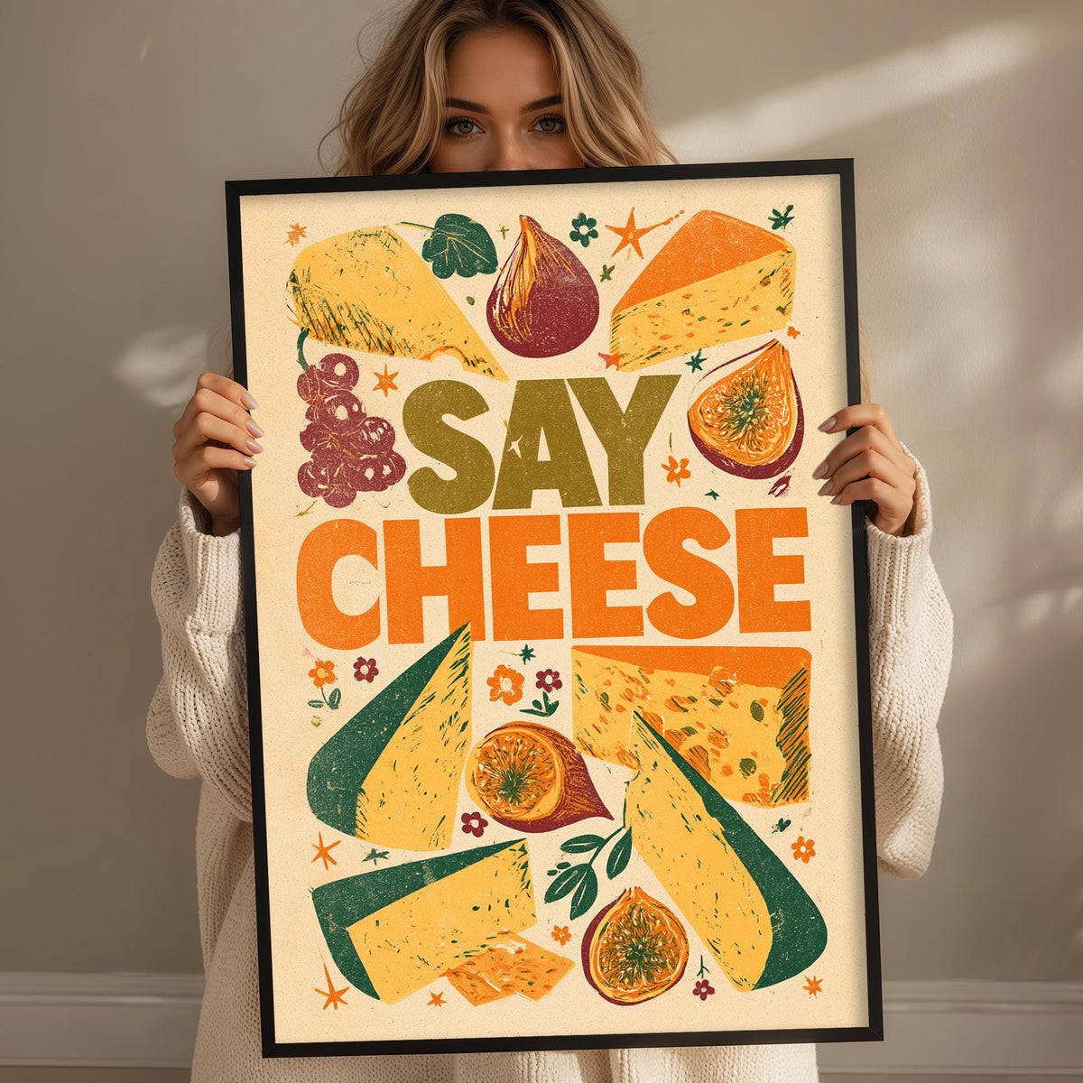 A woman is holding up a framed poster with the text "Say cheese" and various cheese-related illustrations, such as slices, wedges, and other cheese-related objects.