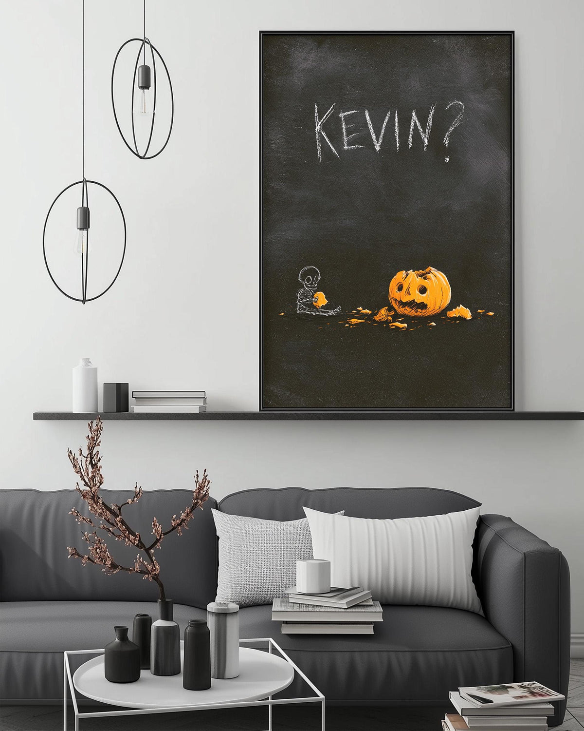 a living room with a gray sofa, a coffee table, and a large black and white picture of a pumpkin with the name "KEVIN?" written on it.