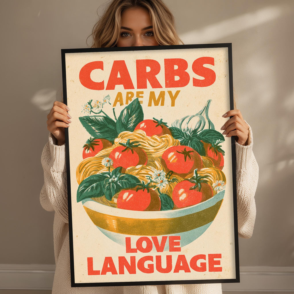 A woman holding a framed poster with a colorful illustration of a bowl of food and the text "CARBS ARE MY LOVE LANGUAGE"