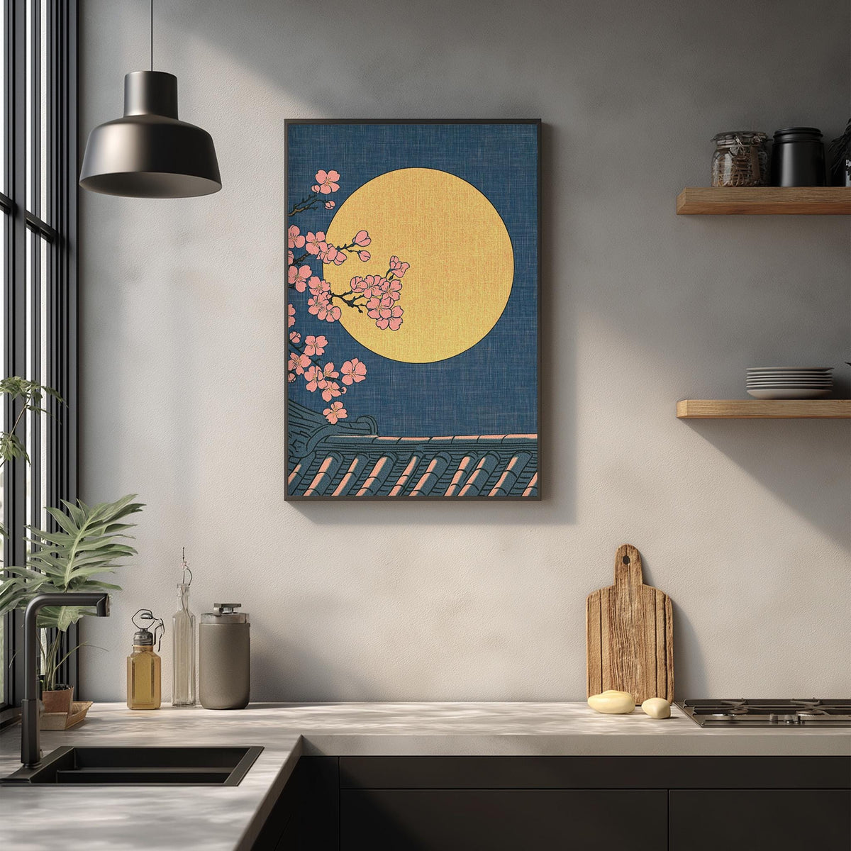 a kitchen counter with a framed artwork depicting a cherry blossom tree with pink flowers against a blue background, and a wooden cutting board on the counter.