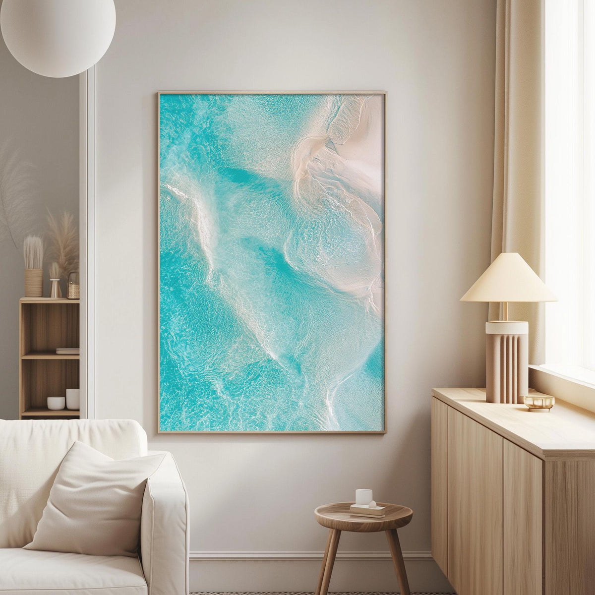 a living room with a large, vibrant painting of turquoise water hanging on the wall. The painting is framed in a wooden frame and is the focal point of the room. The living room also includes a white sofa, a wooden side table, and a lamp on a nearby table.