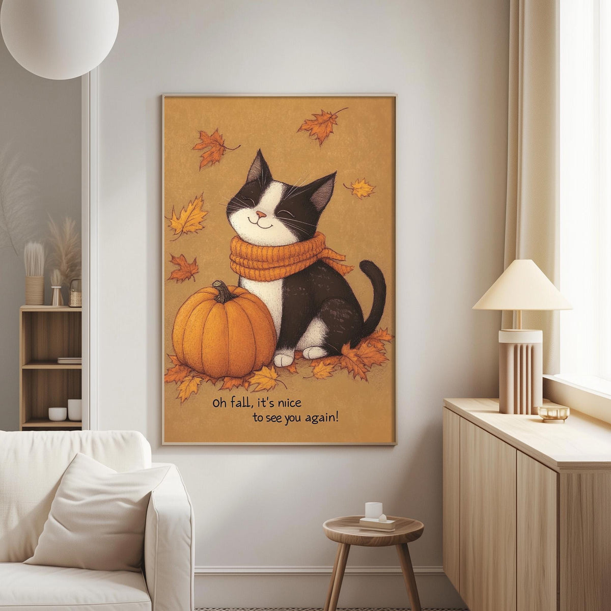 A cozy living room with a framed illustration of a black and white cat sitting next to a pumpkin, surrounded by autumn leaves, and the text "oh fall, it's nice to see you again!"