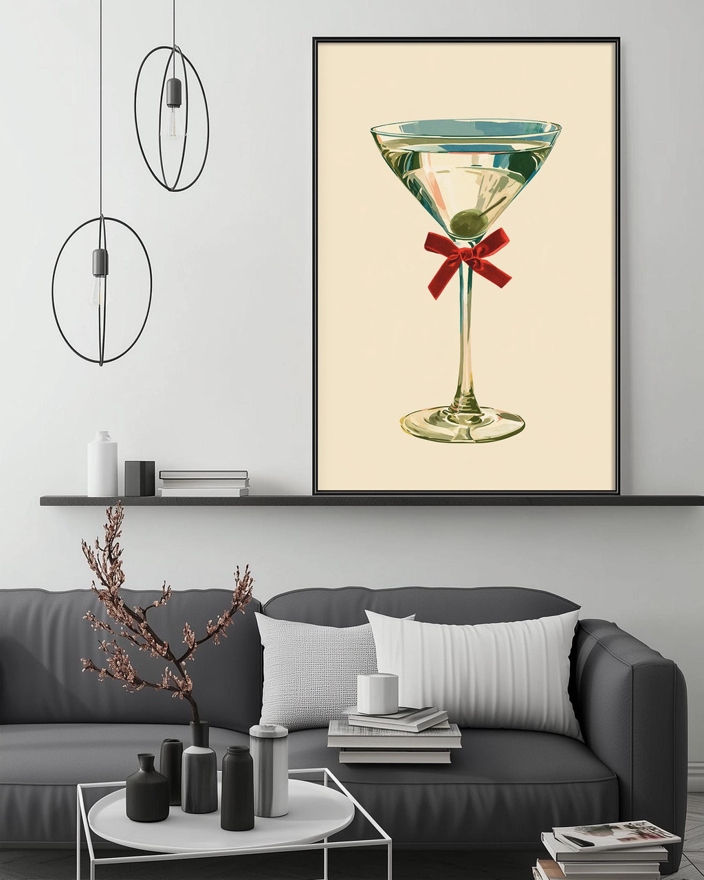 a large framed picture of a martini glass with a red ribbon, hanging on a wall above a gray couch with a coffee table in front of it.