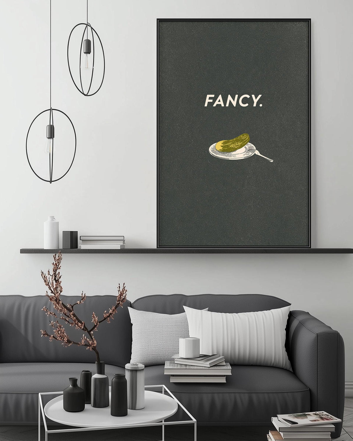 a modern living room with a gray sofa, a coffee table, and a large framed poster on the wall. The poster has a graphic of a plate with a pickle and a fork, accompanied by the word "FANCY."