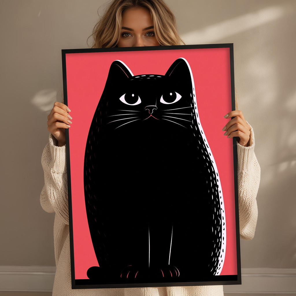 A woman is holding up a framed picture of a black cat with a pink background.