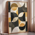 a large abstract painting with a geometric design in black, yellow, and white colors. The painting is displayed on a white wall, and it is leaning against the wall.