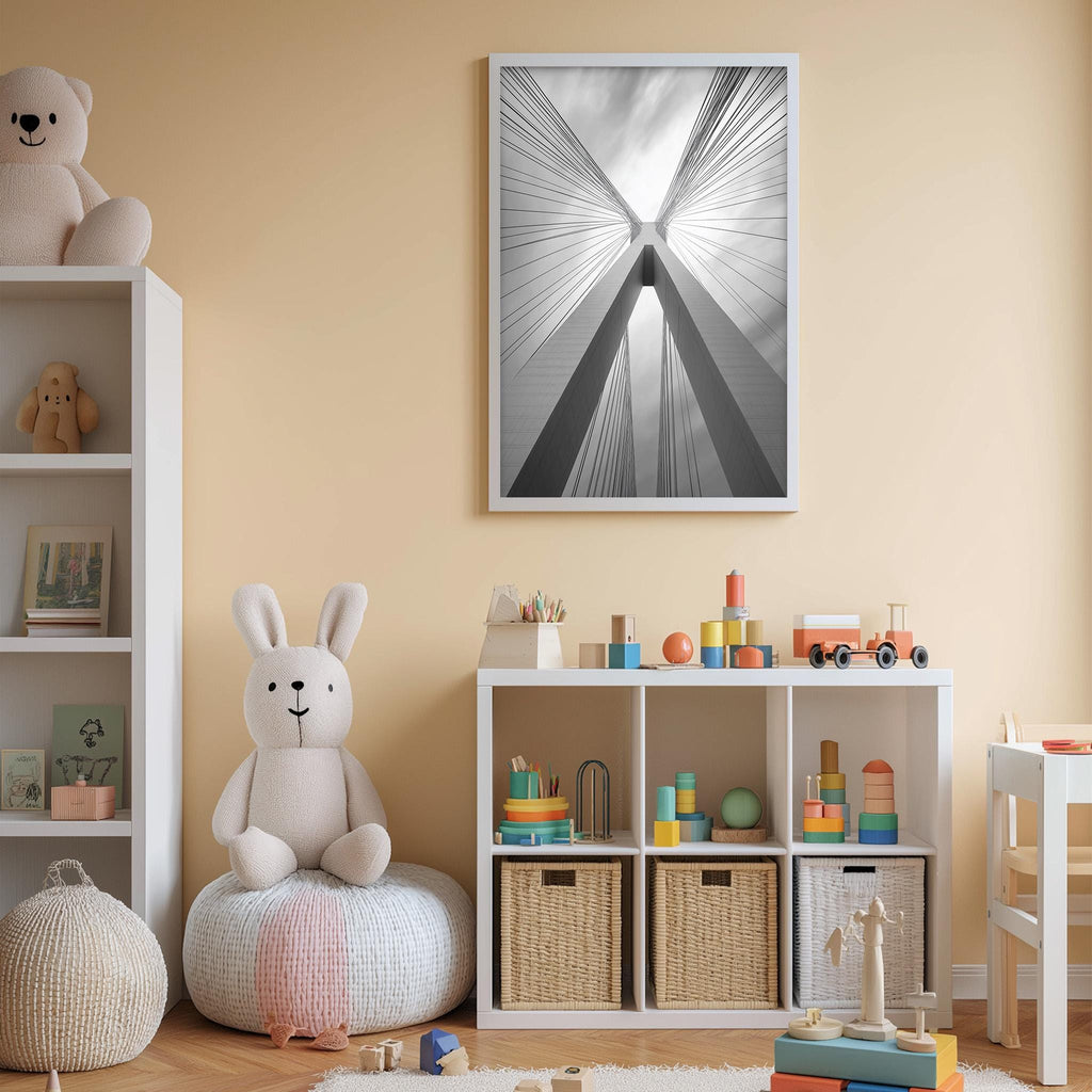 A cozy children's room with a white bookshelf, a stuffed rabbit, and a toy train set. The walls are painted a light peach color, and a framed black and white photograph of a building's cross beams is displayed on the wall.