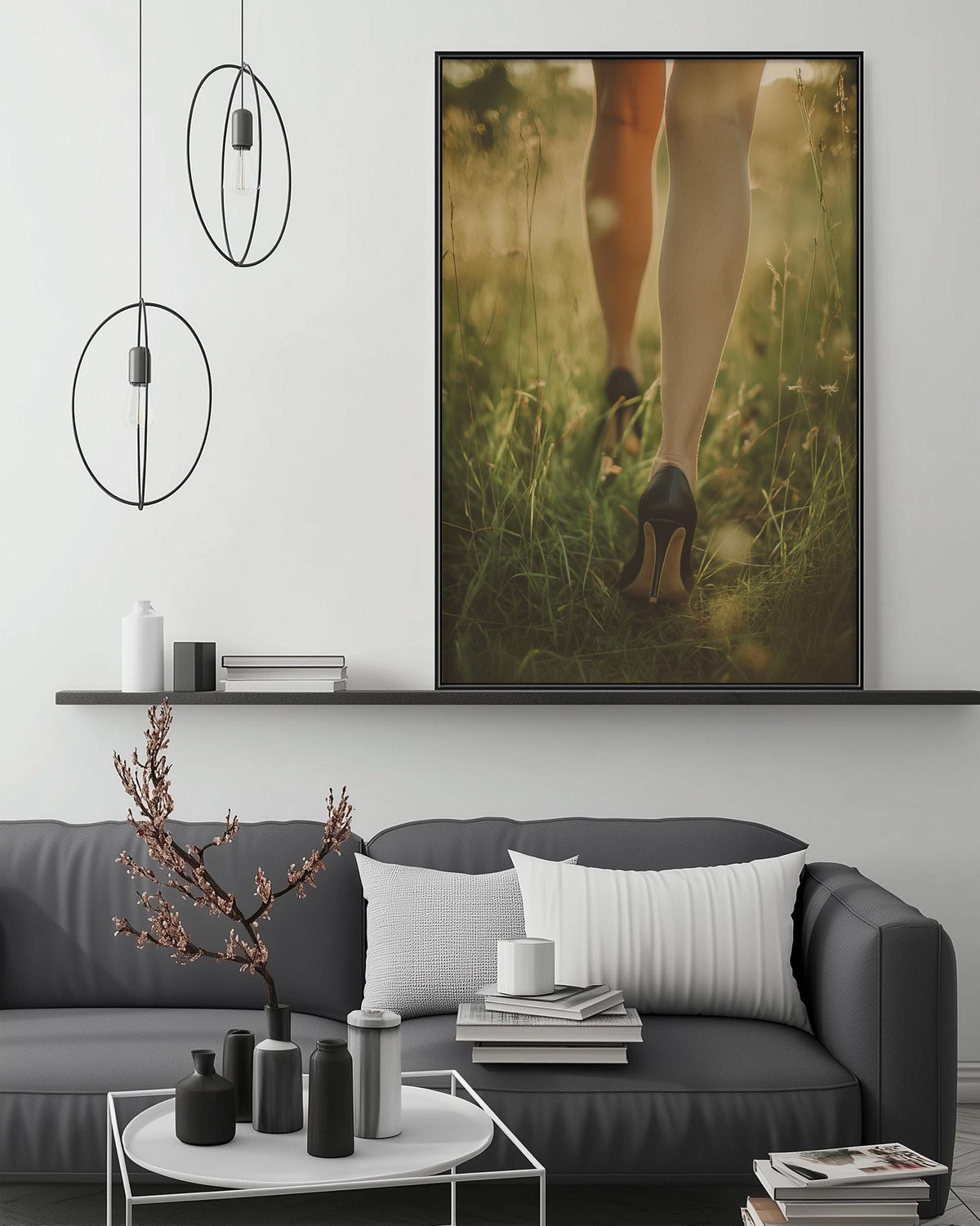 a modern living room with a gray sofa, a coffee table, and a large framed photograph of a woman's legs walking through a field of flowers.