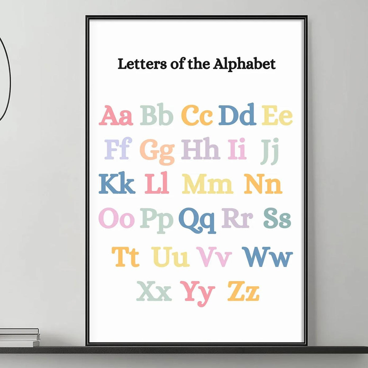 a poster of the alphabet hanging on a wall above a gray couch with a coffee table in front of it.
